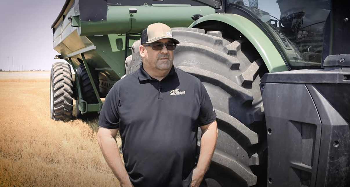 Neil Romick, a 21st Century Equipment Employee, beside a John Deere tractor.